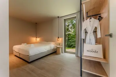 a bedroom with a bed and a dress hanging on a rack at Woodz Lodges in Heusden - Zolder