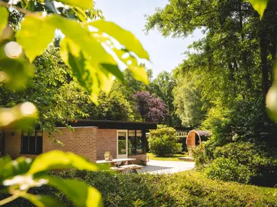 a garden with a brick house with a picnic table at Boshuisje Rekem - Alma with private sauna in Lanaken