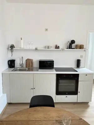 a white kitchen with a sink and a stove at Cosy Alba plein centre Visé in Visé