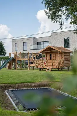 a playground with a wooden house and a slide at NIEUW - De Grenspaal OOST 7P - 3SLPK - SAUNA - LAADPAAL in Riemst