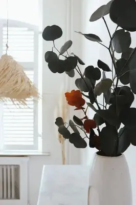 a white vase with a plant in it on a table at Superbe appartement avec cheminée in Verviers