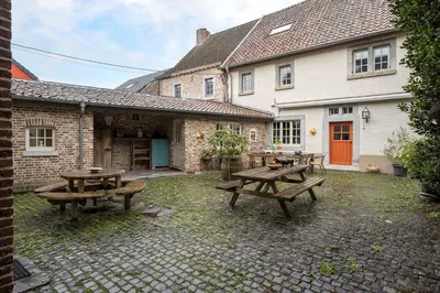 a patio with picnic tables in front of a house at Authentic apartment in Voeren in Voeren