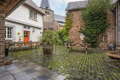 a courtyard with a wooden bench and a building at Beautiful appartment in Voeren in Voeren