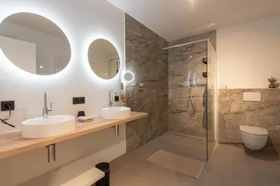 a bathroom with two sinks and a shower at NIEUW De Grenspaal ZUID 2slpk - 4P - SAUNA - LAADPAAL in Riemst