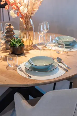 a wooden table with plates and wine glasses on it at NIEUW De Grenspaal ZUID 2slpk - 4P - SAUNA - LAADPAAL in Riemst