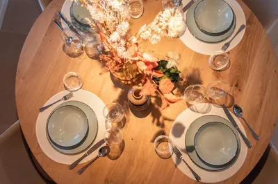 a wooden table with plates and wine glasses on it at NIEUW De Grenspaal ZUID 2slpk - 4P - SAUNA - LAADPAAL in Riemst