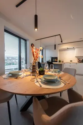 a wooden table with chairs and a dining room at NIEUW De Grenspaal ZUID 2slpk - 4P - SAUNA - LAADPAAL in Riemst