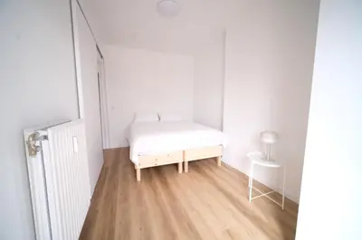 a white bedroom with a bed and a wooden floor at Smart Appart - City Center Liege in Liège