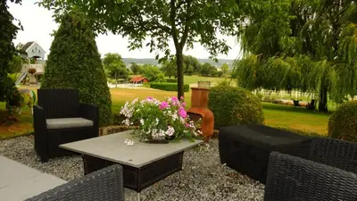 a patio with chairs and a table with flowers on it at Appartement Hoeve Espewey - Leisure only in Hombourg