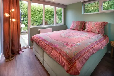 a bedroom with a bed with a pink comforter and windows at Lacuna STILLA by Sonnevijver Residences in Lanaken