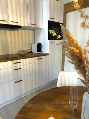 a kitchen with white cabinets and a wooden table at Chalet Hoge Kempen in Zutendaal