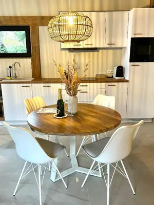 a dining room table with chairs and a bottle of wine at Chalet Hoge Kempen in Zutendaal