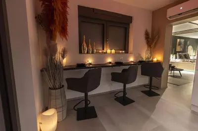 a living room with a bar with chairs and candles at SuiteDreams - Bali Suite Liège in Liège
