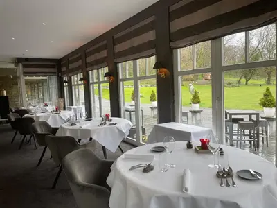 a restaurant with white tables and chairs and windows at Lafarques in Pepinster