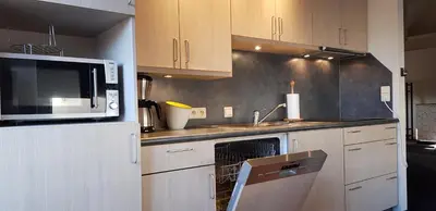 a kitchen with white cabinets and a microwave and a sink at Apartment Campinor in Pelt