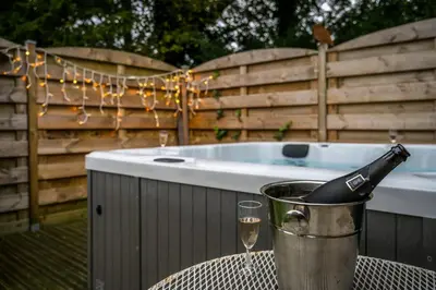 a bottle of champagne in a bucket next to a tub at Gîte La Vieille Ferme Chaudfontaine et son jacuzzi in Chaudfontaine