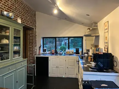 a kitchen with white cabinets and a brick wall at Vakantiehuis Eksel in Hechtel-Eksel
