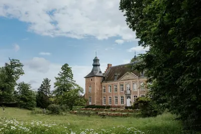 an old brick building with a tower on top of a field at Château de Looz in Borgloon