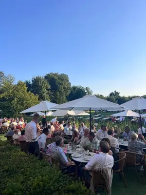 a group of people sitting at tables with umbrellas at Château de Looz in Borgloon