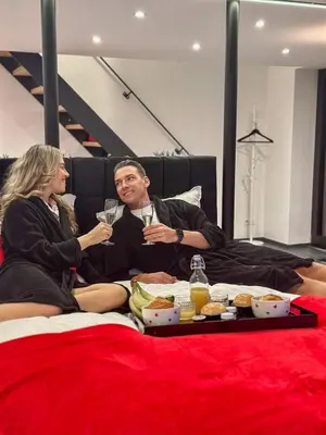 a man and woman sitting on a bed drinking champagne at LCforyou in Juprelle