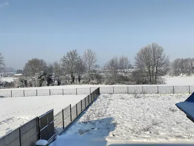 a snowy field with a fence and a snow covered field at Sluizen aan de Jeker in Tongeren