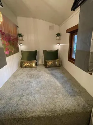a small room with two pillows and a window at Pipowagen de Zwaan in Hoge Kempen nabij Maastricht in Lanaken