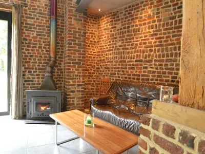 a living room with a leather couch and a brick wall at Teuven Farmhouse for 24 Guests in Teuven