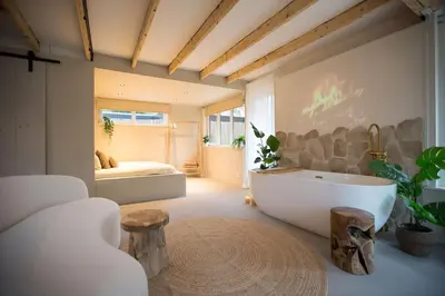 a bathroom with a tub and a bedroom with a bed at Ontspan huisje: wellness in de natuur in Lanaken