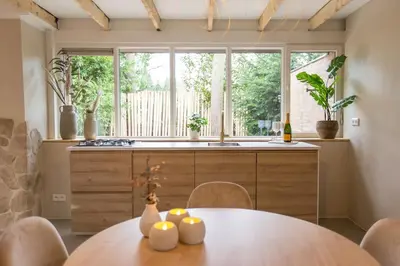 a kitchen with a table and a large window at Ontspan huisje: wellness in de natuur in Lanaken