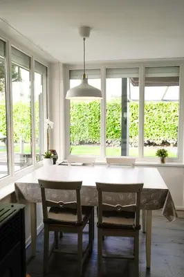 a dining room with a table and chairs and windows at Boshuisje De Eekhoorn in Lanaken