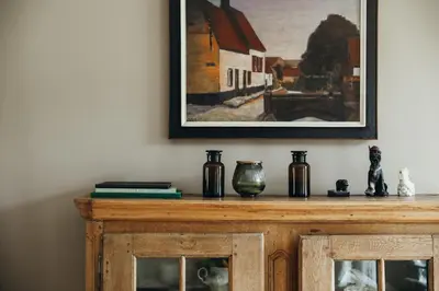 a wooden cabinet with a painting on the wall at Au pied du Pré by WelcHome in Verviers