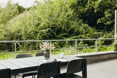 a table with chairs and a vase of flowers on a patio at Au pied du Pré by WelcHome in Verviers