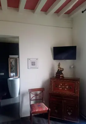 a room with a chair and a dresser and a tv at KolMojen in Sint-Truiden