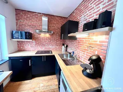 a kitchen with a brick wall and a sink at Le Loft liégeois - Au coeur de la cité in Liège