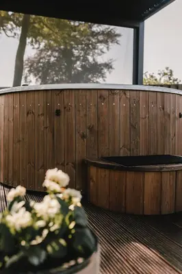 a wooden fence with a hot tub and a vase of flowers at Maison Idyllique in Bree