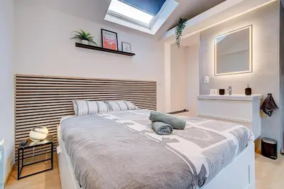 a bedroom with a large bed with a wooden headboard at LIÉGE - Le cocon de Chênée in Chênée