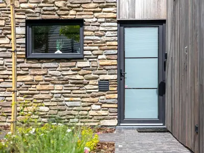 a stone house with a door and a window at Thalor in Zutendaal