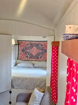 a small bedroom with a bed and a rug on the wall at pipowagen met prive Hot tub in Lanaken