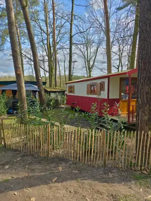 a small red and white trailer in a forest at pipowagen met prive Hot tub in Lanaken