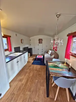 a kitchen and living room with a table and a couch at pipowagen met prive Hot tub in Lanaken