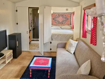 a living room with a couch and a bed at pipowagen met prive Hot tub in Lanaken