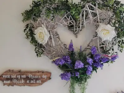 a heart wreath on a wall with flowers at B&B De Watering in Lommel