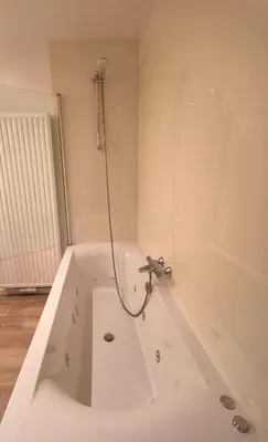 a white bath tub with a shower in a bathroom at Ten Velde - vakantiewoning 12 personen - sauna - bubbelbad in Hoeselt