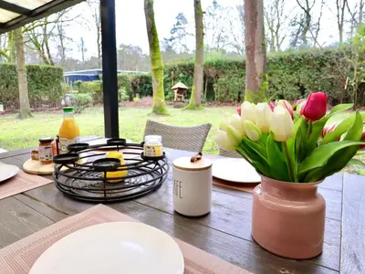 a wooden table with a vase of flowers on it at Sonnig Bungalow in Lanaken