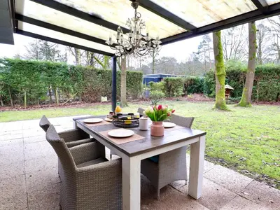 a dining table with chairs and a chandelier at Sonnig Bungalow in Lanaken