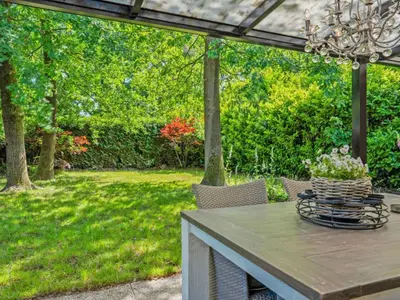 a patio with a table and chairs in a yard at Sonnig Bungalow in Lanaken