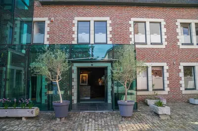a brick building with two potted trees in front of it at Hôtel Au Comte de Mercy in Oupeye