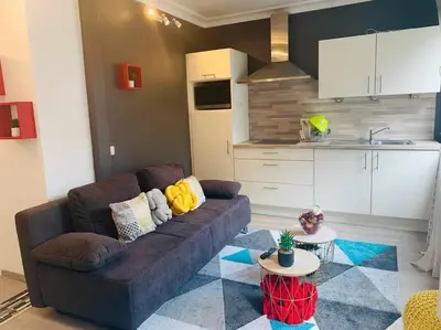 a living room with a couch and a kitchen at Appartement très proche médiacité - centre ville in Liège