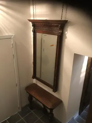 a mirror on a wall with a wooden bench at De Pelgrim in Tongeren