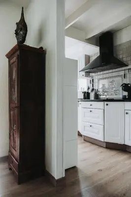 a kitchen with white cabinets and a vase on top of a cabinet at Huisje Mezengroet in Lanaken